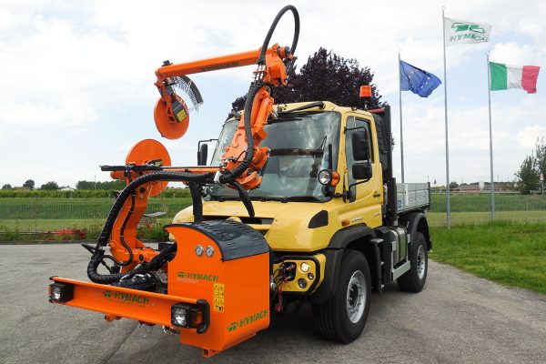 Desbrozadora de paso alto ROAD-EAGLE MAXI UF de Hymach para Unimog, para cortar la hierba alrededor de los soportes de la barrera de seguridad a lo largo de la carretera.